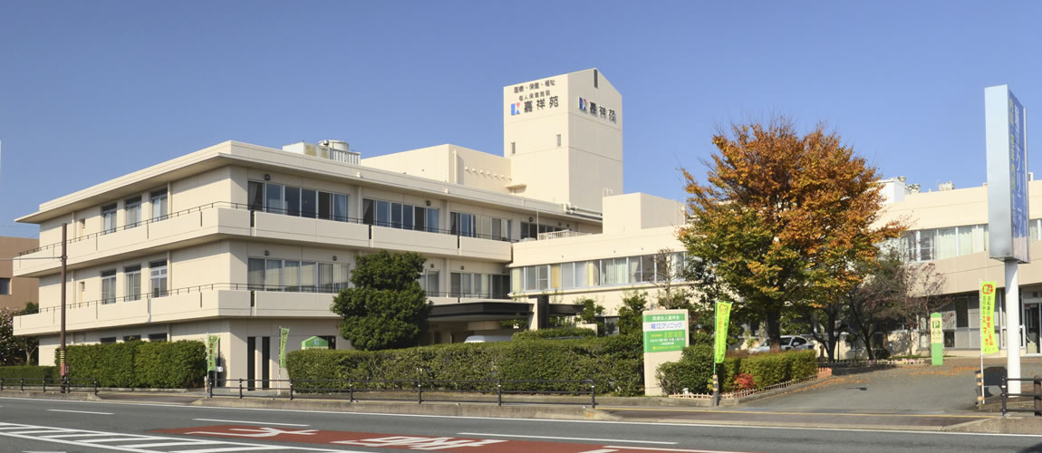 介護施設の建物外観。複数階建てのモダン設計の施設。秋の季節。